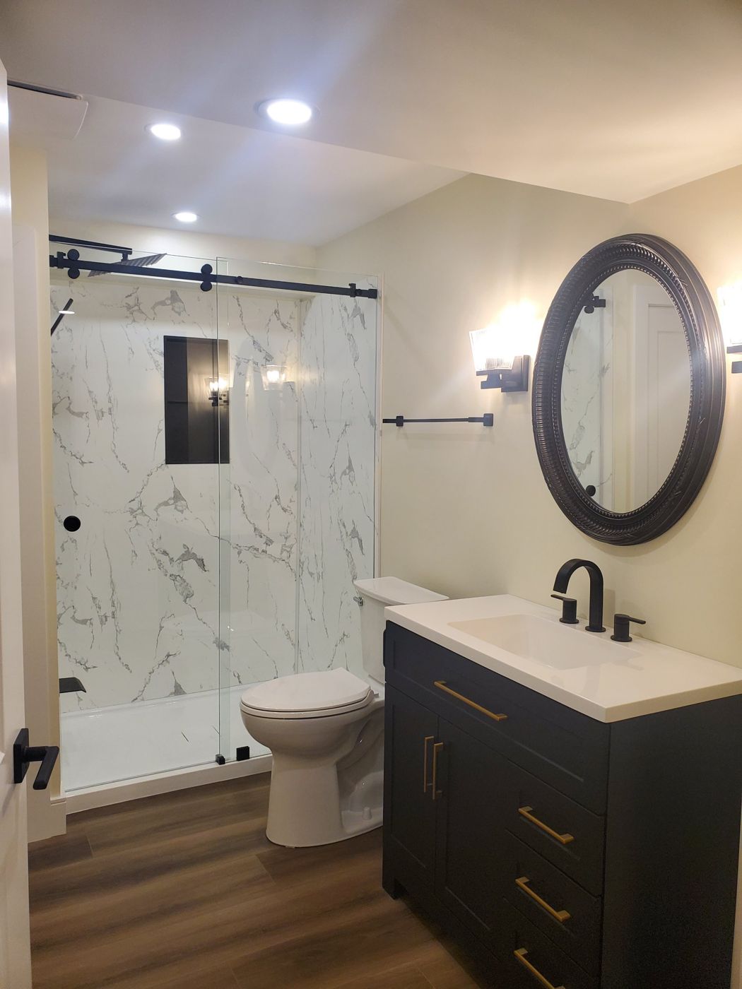 Bathroom with a marble look shower, sliding glass door and dark vanity