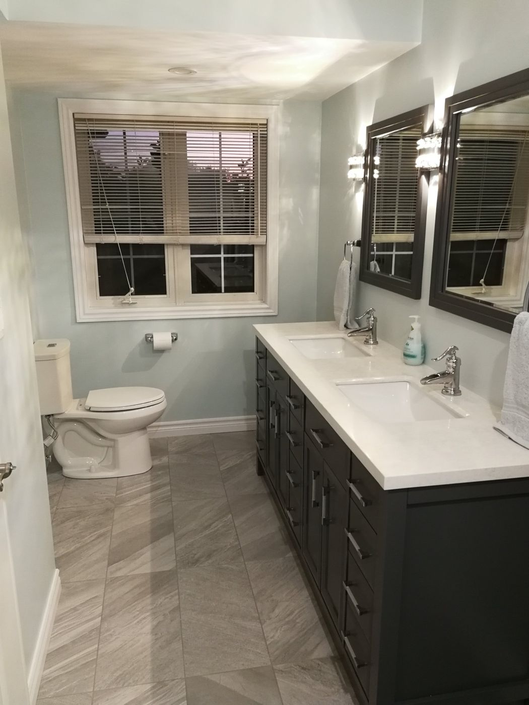 Renovated bathroom with a double vanity, tile floor and trimmed window