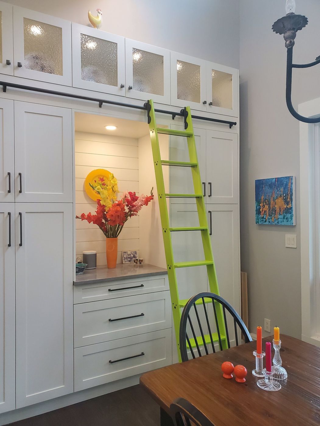 Lime green rolling ladder on white kitchen cabinetry