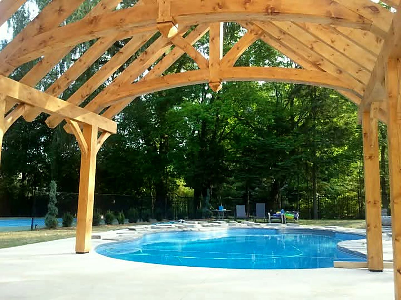 View from under a timber pavilion roof toward a pool