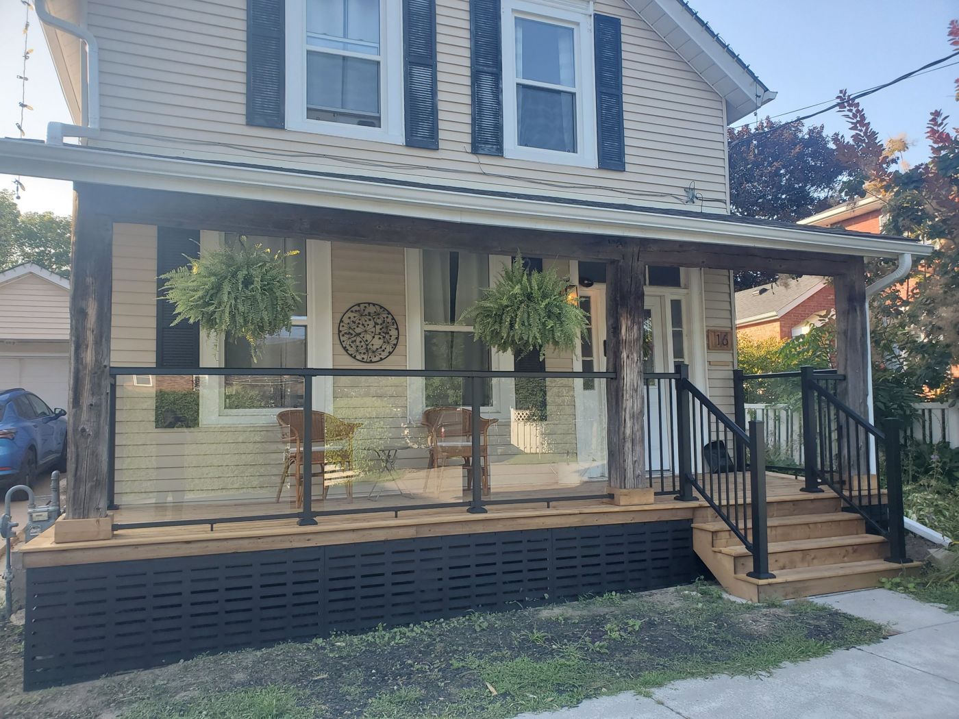Rebuilt front porch with cedar deck, glass railing and black skirting