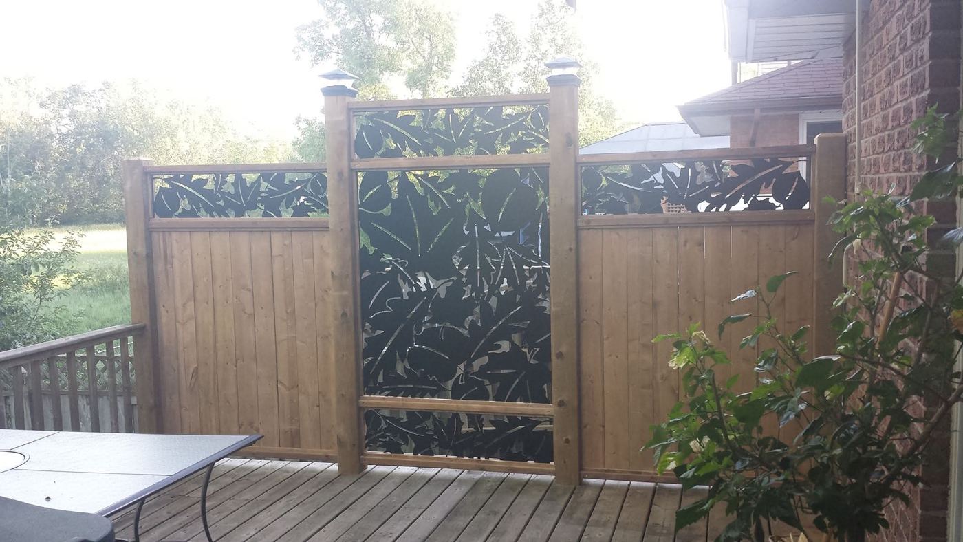 Cedar privacy wall with cut metal leaf panels on a deck